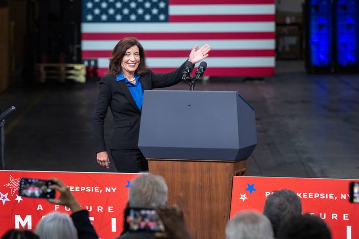 Gov. Kathy Hochul walks to a podium with an American flag in the background.